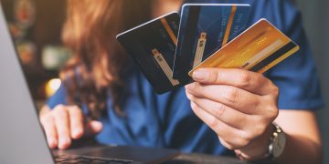 A woman holding credit cards while using laptop computer