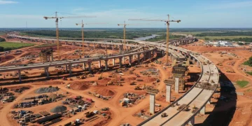Vista aérea de um canteiro de obras de grande porte no Brasil, com pontes e rodovias em construção, simbolizando o avanço da infraestrutura.